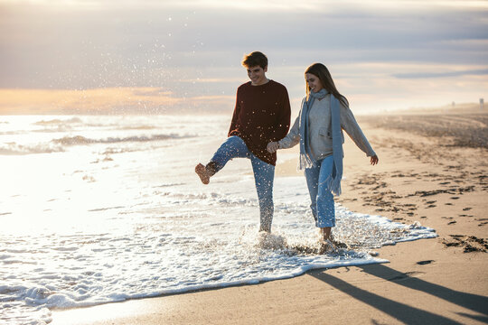 Beautiful young couple in love walking together in a cold winter day on the beach.