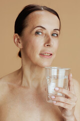 modern woman with glass of water against beige background