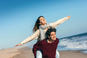 Beautiful young couple in love enjoying the day in a cold winter on the beach.