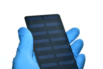 Macro photography of mini solar panel in hand with blue protective glove isolated on white background