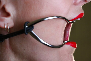 Sexy BDSM Fetisch Model mit roten Lippen und Mundspreizer / Knebel mit offenem Mund