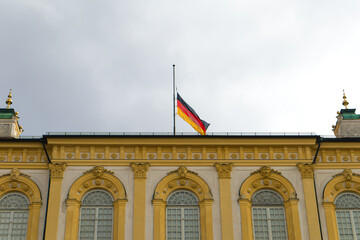 Obraz premium The flag of Germany is developing.The flag of Germany is on the building.The symbol of Germany.A beautiful building with a flag. Flag on the flagpole.Attraction.Old building.Government of Germany.sky.