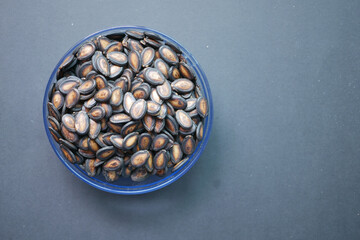 top view of melon seeds in a bowl on black background 