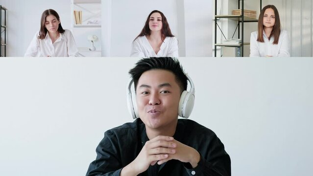 Video interview. Online meeting. Web conference. Confident man in headphones speaking to female business colleagues online at digital office.