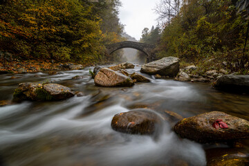 il torrente maira si insinua tra le rocce sotto il ponte del diavolo in una giornata d'autunno