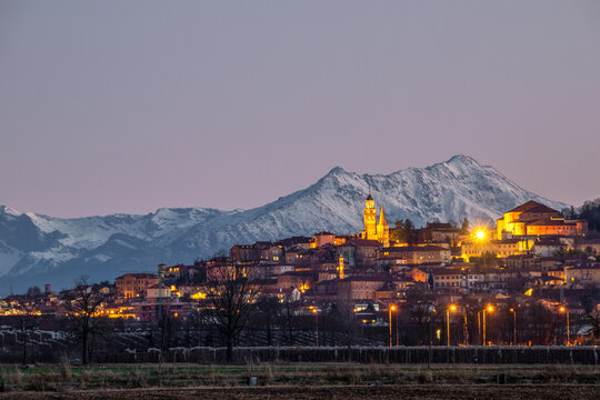 La città di saluzzo illuminata dalle sue luci al tramonto e la bisalta sullo sfondo