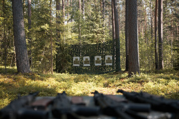 Four targets for shooters are hung on a green canvas in the forest.