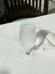 Glass of water sweats in summer heat at fine restaurant on linen table cloth 
