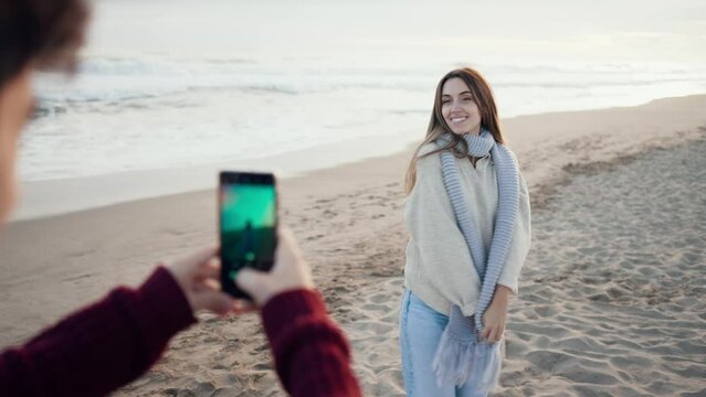 Video of happy young couple taking photos with smartphone on a cold winter in the beach.