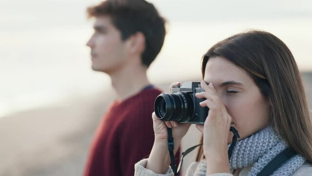 Video of happy young couple taking photos with camera on a cold winter in the beach.