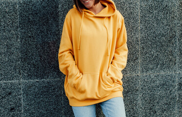 Handsome young female wearing yellow blank hoodie with space for your logo or design. Mockup for...