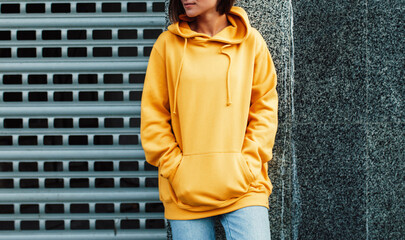 Handsome young female wearing yellow blank hoodie with space for your logo or design. Mockup for...