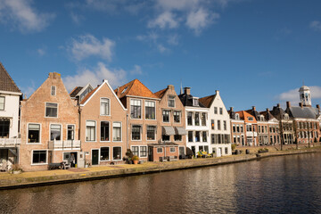 Fototapeta na wymiar waterside residential houses on the edge of the river kleindiep waterway in Dokkum, Friesland, Netherlands Holland. old town hall in town centre with bridge on pleasant sunny day