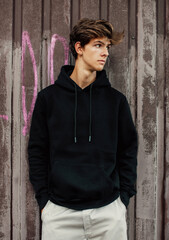 City portrait of handsome young guy wearing black blank hoodie or sweatshirt with space for your logo or design. Mockup for print