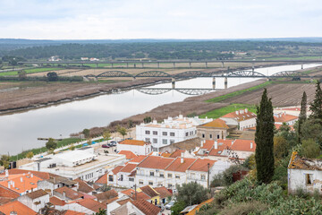 Fototapeta na wymiar partial view over Alcácer do Sal city and a railway bridge over Sado river, district of Setúbal, Alentejo, Portugal - December 2022