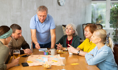 Older men and women playing board game together