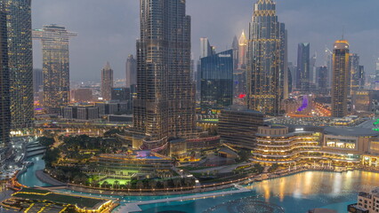 Skyscrapers rising above Dubai downtown day to night timelapse surrounded by modern buildings aerial top view