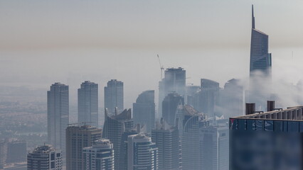 Fog covered skyscrapers in JLT district aerial timelapse.