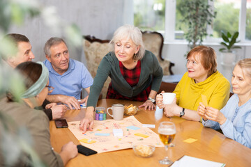Fototapeta premium Retirees play board games and drink tea with cookies