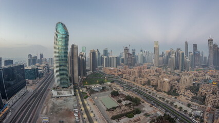 Naklejka na ściany i meble Dubai's business bay towers aerial night to day timelapse. Rooftop view of some skyscrapers