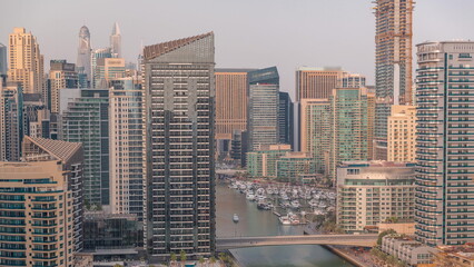 Dubai Marina with several boat and yachts parked in harbor and skyscrapers around canal aerial timelapse.