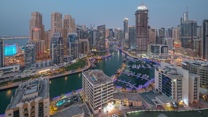 Dubai Marina with several boat and yachts parked in harbor and skyscrapers around canal aerial day to night timelapse.