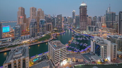Naklejka premium Dubai Marina with several boat and yachts parked in harbor and skyscrapers around canal aerial day to night timelapse.