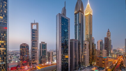 Obraz premium Aerial view of Dubai International Financial District with many skyscrapers day to night timelapse.