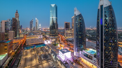 Naklejka na ściany i meble Aerial view of Dubai International Financial District with many skyscrapers day to night timelapse.