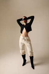 Studio portrait of confident young woman wearing sunglasses posing indoor.