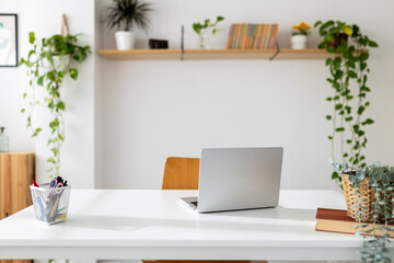 Laptop computer on table in bright room of home office workspace