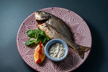 dorado fish with lemon on a platter on a gray background