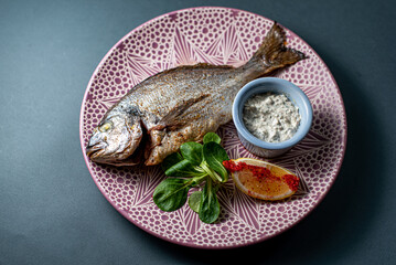 dorado fish with lemon on a platter on a gray background