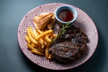 French fries on gray background with steak and ketchup