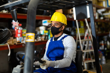 Forklift driver in protective mask at the warehouse of a hardware store