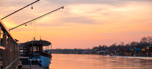 Beautiful sunset on the river with a boat and houses on the other side