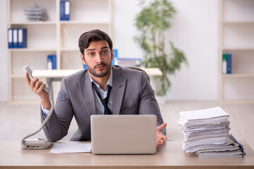 Naklejka premium Young male employee and too much work in the office