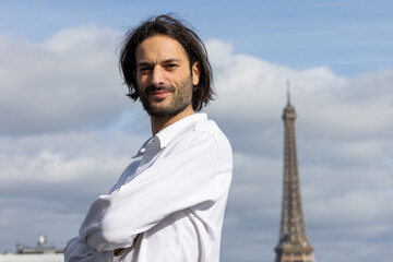Portrait d'un beau jeune homme brun souriant avec la Tour Eiffel et Paris en arrière plan