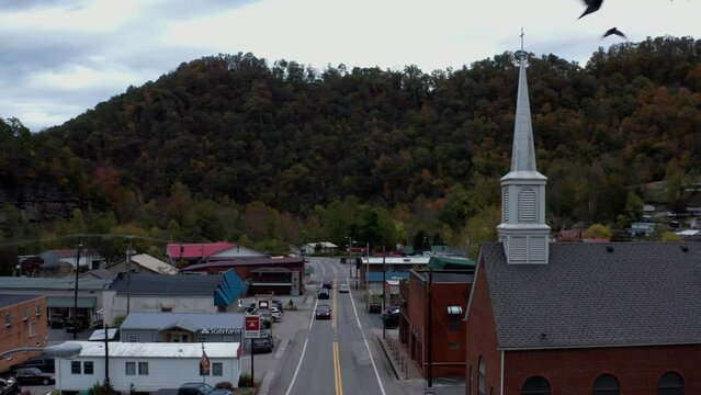 Gilbert, West Virginia -small town and white church steeple. Aerial reveal shot.