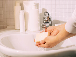 Woman washes her hands with soap over sink in bathroom. Hygiene and health cleanliness and body care