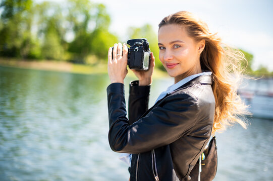 Young smiling woman holding a reflex camera outdoor