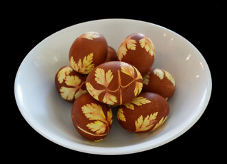 Naturally decorated brown color Easter egg close up on a white plate