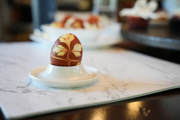 Decorated Easter egg close up on a white plate