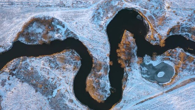 winter aerial top view to river bending in fields