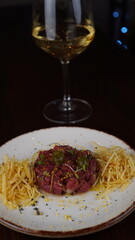 Close up of delicious Steak Tertar with french fries and glass of red wine in gourmet restaurant background, healthy food, luxurious life