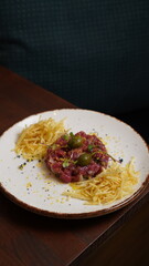 Close up of delicious Steak Tertar with french fries and glass of red wine in gourmet restaurant background, healthy food, luxurious life