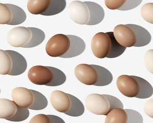 Easter eggs seamless pattern on white background, shadow at sunlight. Chicken eggs with dyed pastel beige gradient color eggshells, food Easter celebration concept, top view, trend aesthetic flat lay