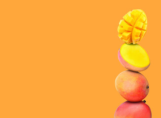Stacked fresh mango fruits on orange background, space for text
