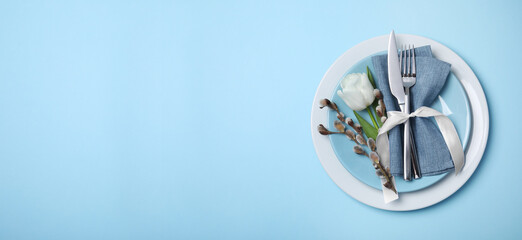 Festive Easter table setting with willow twigs and tulip on light blue background, top view. Banner design with space for text