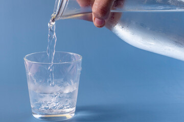Glass of water being filled on blue background